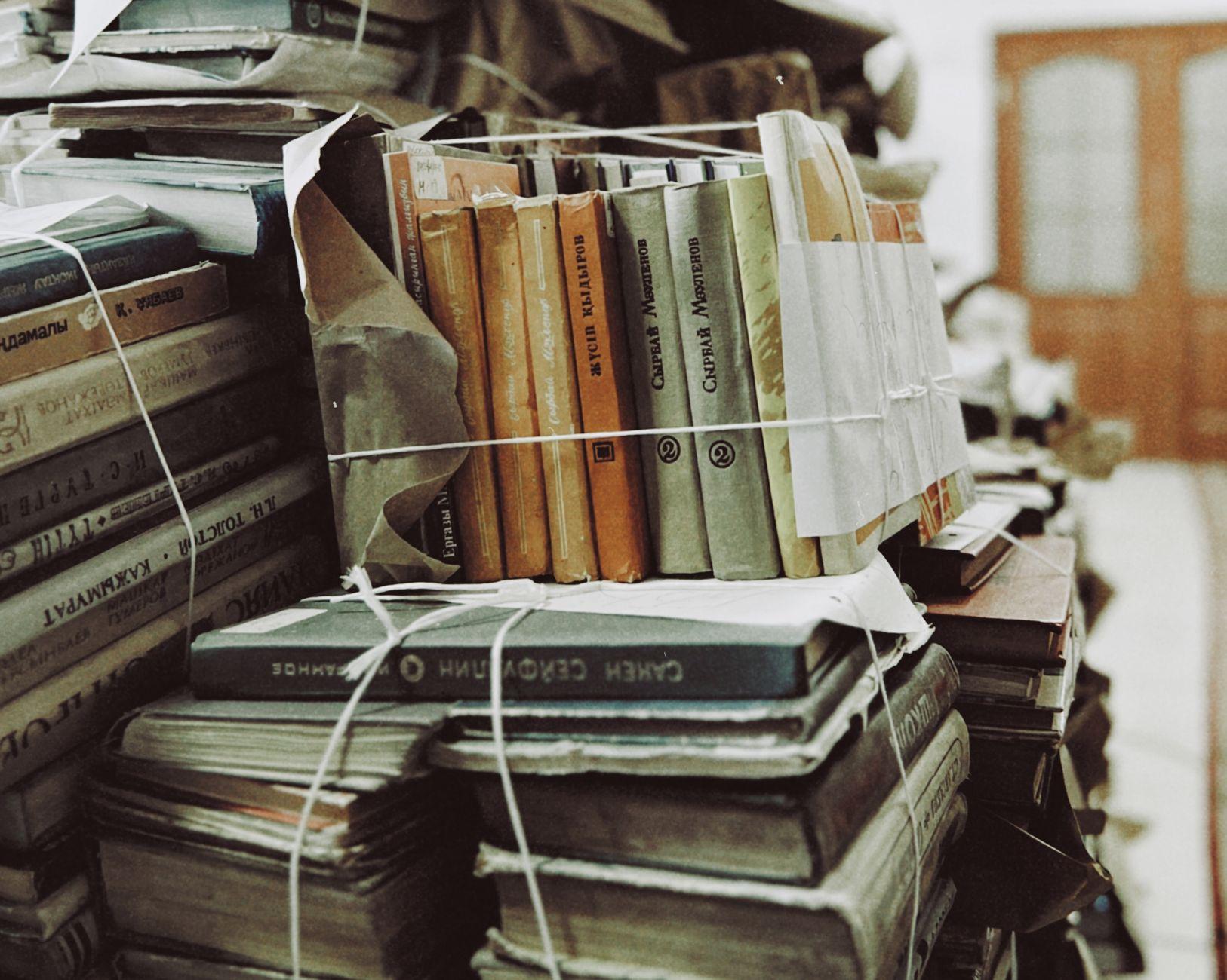 A stack of secondhand paperback books tied with string, ready to be posted