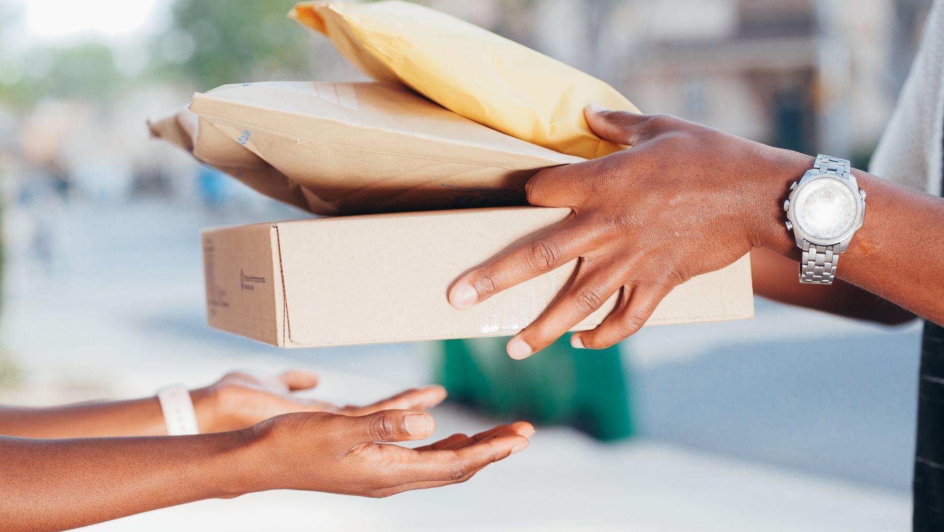 Two hands exchanging a small wrapped parcel outdoors